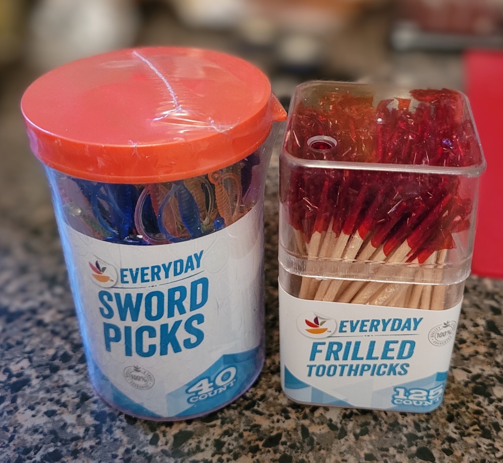 A container of sword shaped toothpicks, and a container of toothpicks with red frilly cellophane
